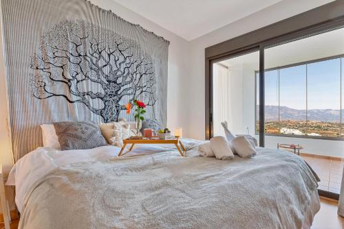 a bedroom with a bed with a tree mural on the wall at Calita 109 Mijas Costa - Málaga in La Cala de Mijas