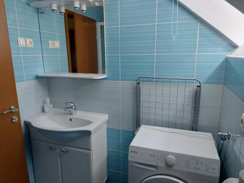 a blue tiled bathroom with a toilet and a sink at Apartments and Rooms Martuljk in Kranjska Gora