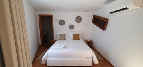 a bedroom with a white bed and two clocks on the wall at Casas de Campo da Barroca in Tabosa