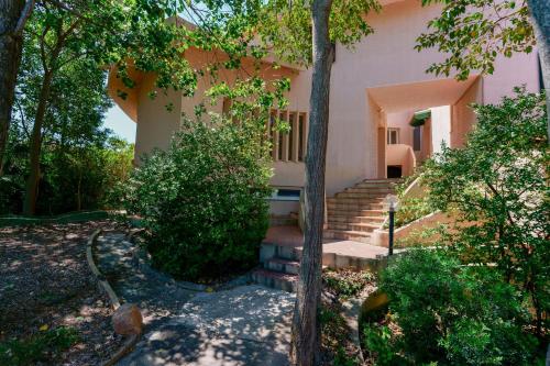 una casa con escaleras y árboles delante de ella en B&B Villa Zola en Capoterra