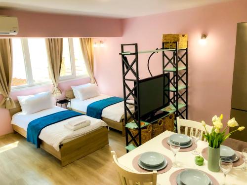 a room with two beds and a table and a tv at Top Location !!FREE parking!! "Belle Mer" Sea Garden, Beach and Promenades in Burgas City