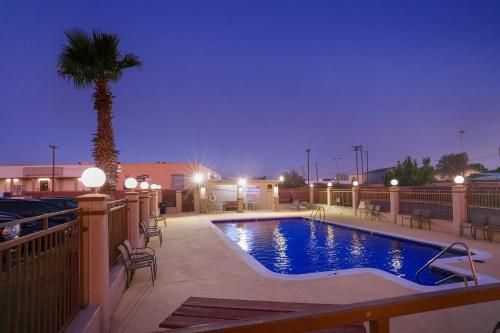 a swimming pool with a palm tree on a patio at Carlsbad Inn , New Mexico in Carlsbad