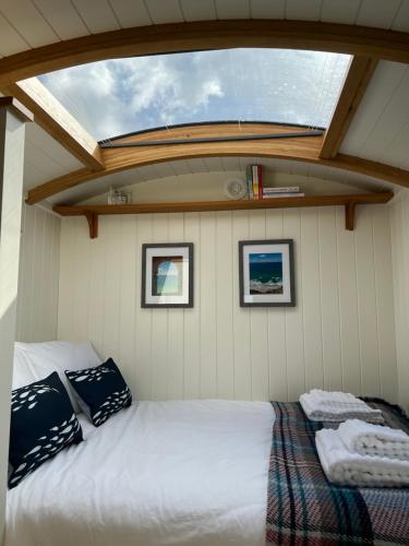 a bed in the back of a boat with a window at Toms Hut and Robins Rest Shepherd Huts near Wadebridge in Wadebridge