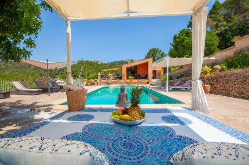 a table with a bowl of fruit on it next to a pool at Finca Sa Fuente in Felanitx