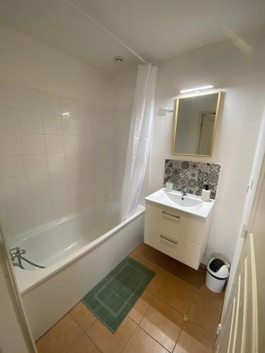 łazienka z wanną, umywalką i lustrem w obiekcie Chez Mathieu w mieście Gallargues-Le-Montueux