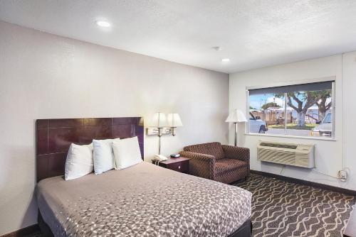 ein Hotelzimmer mit einem Bett, einem Stuhl und einem Fenster in der Unterkunft Carlsbad Inn , New Mexico in Carlsbad