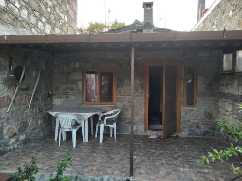 a patio with a table and chairs in a stone building at Küçük taş evde otantik bir tatil keyfi… in Ayvacık