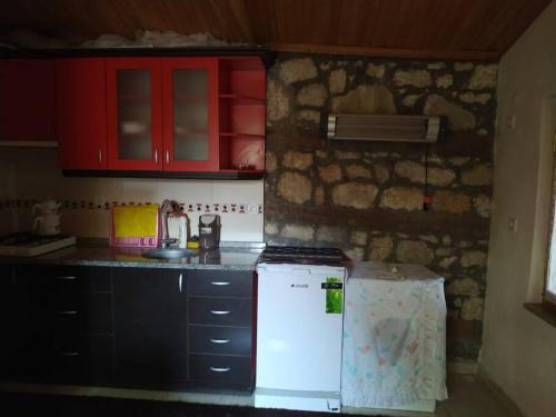 a kitchen with red cabinets and a white refrigerator at Küçük taş evde otantik bir tatil keyfi… in Ayvacık