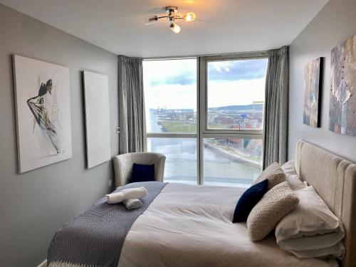 Titanic and Sea View Belfast 2 bedroom Apartment City Centre في بلفاست: غرفة نوم بسرير ونافذة كبيرة
