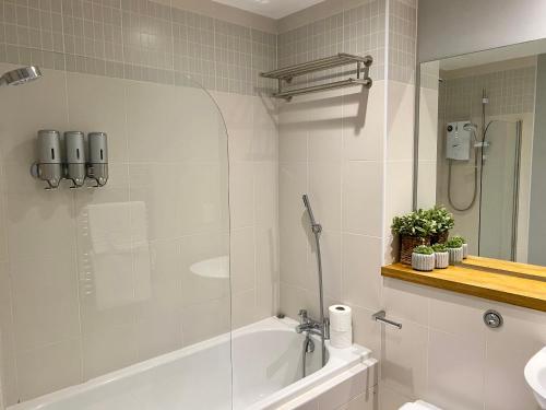 a bathroom with a shower and a tub and a sink at Titanic and Sea View Belfast 2 bedroom Apartment City Centre in Belfast