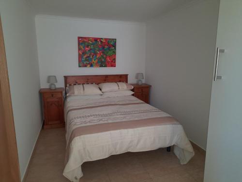a bedroom with a bed and two night stands and a painting at Elizabeth Apartment in Pedrógão Grande