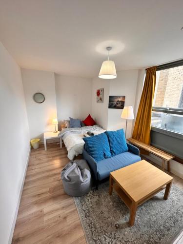 a living room with a bed and a blue couch at 2 modern double rooms in the heart of Brick lane in London