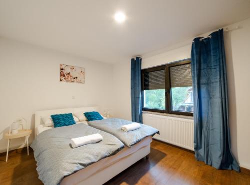 a bedroom with a bed with blue curtains and a window at Jankovi Dvori in Rakovica