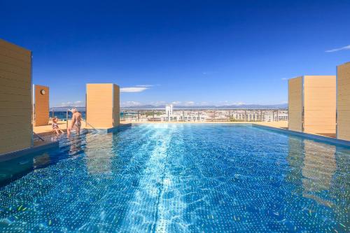 a woman and a child are standing in a swimming pool at UHC Central Park Apartments in Salou