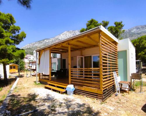 une petite cabane en bois avec une montagne en arrière-plan dans l'établissement Mobile Homes Aurea Maris - Kamp Dole Živogošće, à Živogošće