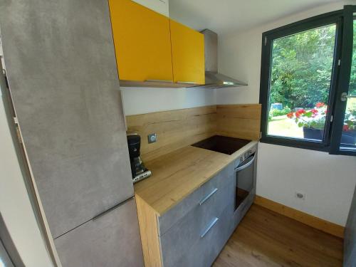 a small kitchen with yellow cabinets and a window at Appartement en rez de jardin in Thénésol