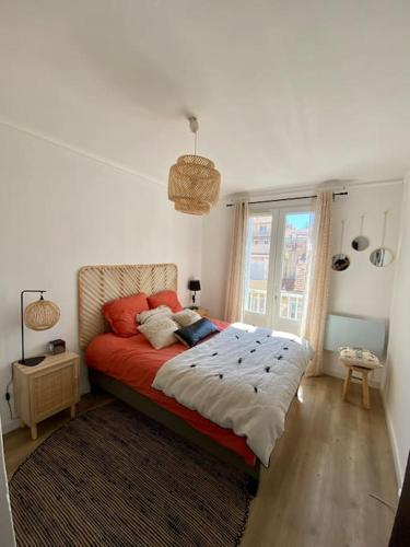 une chambre avec un lit avec des oreillers rouges et une fenêtre dans l'établissement Charmant T2 à proximité de la plage des Catalans, à Marseille