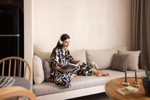 a woman sitting on a couch reading a book at Pnoes Luxury Suites in Paliouri