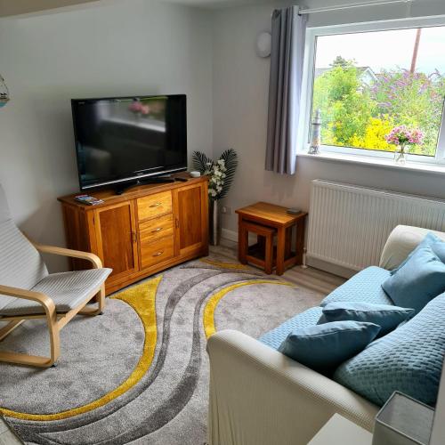 a living room with a couch and a tv at Benllech Beach in Benllech