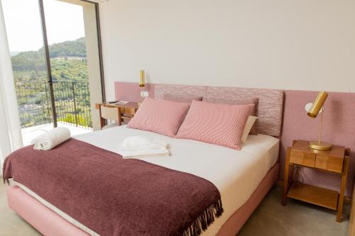 - une chambre avec un lit doté d'oreillers roses et d'une fenêtre dans l'établissement QUINTA ALTO DO RIO, à Cinfães