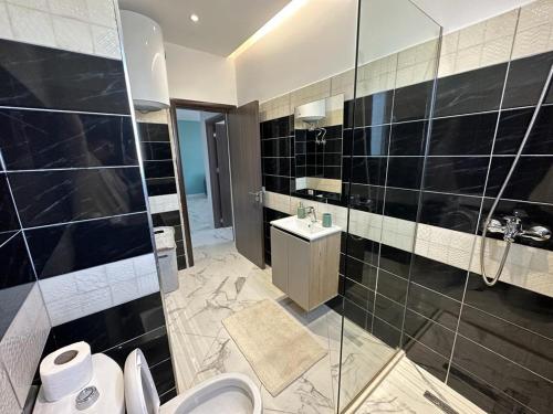 ein Bad mit einer Dusche, einem WC und einem Waschbecken in der Unterkunft TreA Accomodations - Despacito Deluxe Sea View in Vlorë