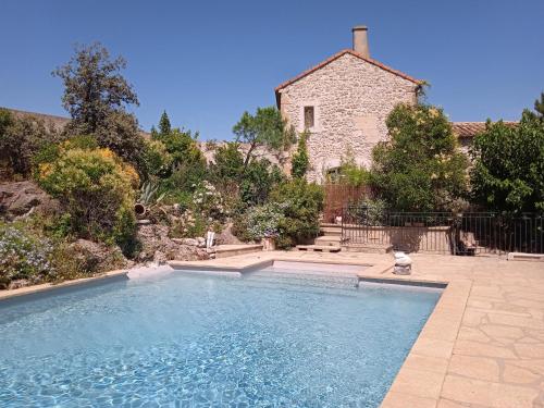 uma piscina em frente a uma casa de pedra em Mazet Des Artistes em Mouriès