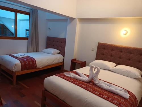 a hotel room with two beds with towels on them at Paqarina San Blas in Cusco