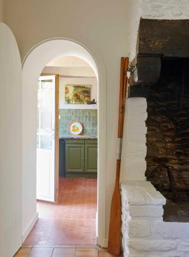 an archway in a room with a counter and a kitchen at La Longère de l'Amiral c'est au choix la Maison de l'Amiral jusqu'à 10 personnes ou le Carré de l'Amiral jusqu'à 4 personnes in Moëlan-sur-Mer