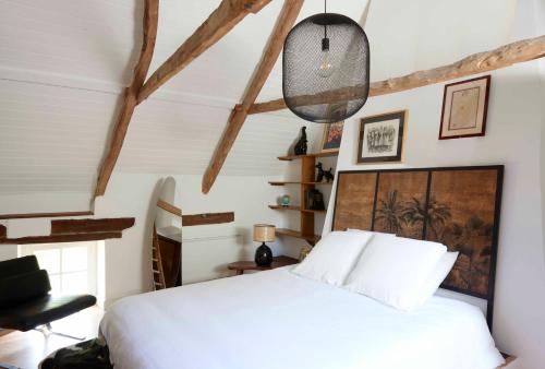a bedroom with a white bed and a black chair at La Longère de l'Amiral c'est au choix la Maison de l'Amiral jusqu'à 10 personnes ou le Carré de l'Amiral jusqu'à 4 personnes in Moëlan-sur-Mer