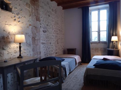 穆里耶的住宿－Mazet Des Artistes，一间卧室设有两张床、一张桌子和一个窗口。