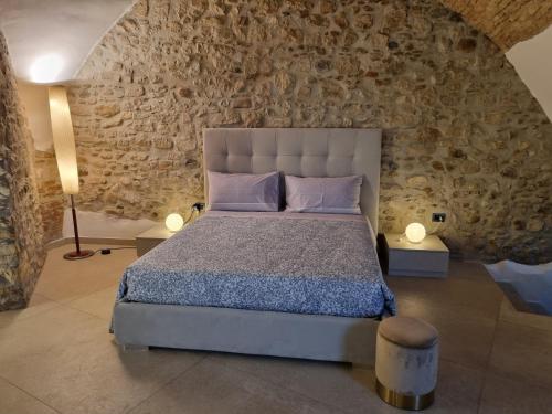1 dormitorio con cama y pared de piedra en B&B SUITE D'AVALOS, en Venosa