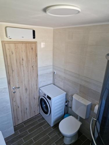 a bathroom with a toilet and a washing machine at Apartma Tija in Tolmin