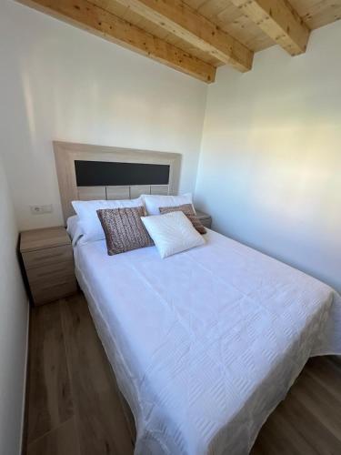 a bedroom with a large white bed with wooden ceilings at A Casa de Fóra in Muros