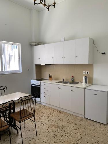 uma cozinha com armários brancos e uma mesa e cadeiras em Graffiti Ground Floor em Atenas