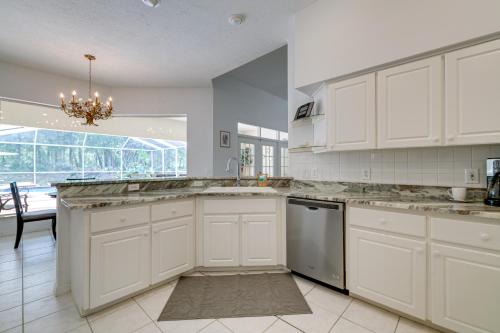 a kitchen with white cabinets and a chandelier at 4 Mi to Rainbow Springs Dunnellon Villa with Pool! in Dunnellon