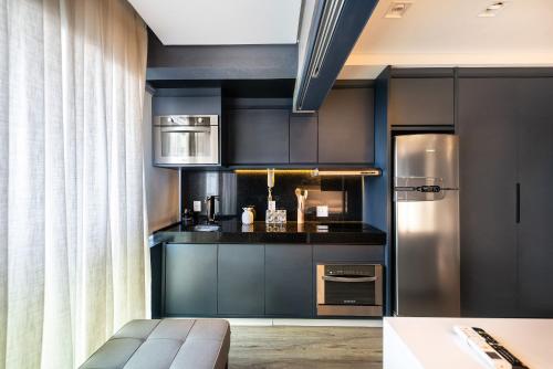 cocina con armarios negros y nevera de acero inoxidable en VU3 - Estilo e Conforto: Studio de Luxo Próx. ao Allianz Parque, en São Paulo