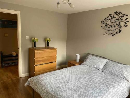 a bedroom with a bed and a dresser with flowers on it at Spacious Ground Floor 2 Bed by Lains Lettings in Aberdeen