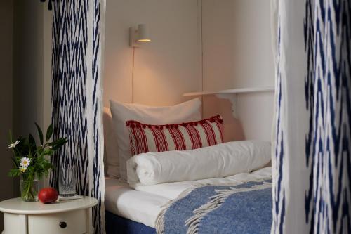 a white bed with a red pillow and a table at Hotell Bäckagården in Ystad