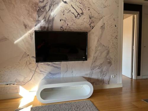 a living room with a tv on a marble wall at Relájate después de patear Madrid in Madrid