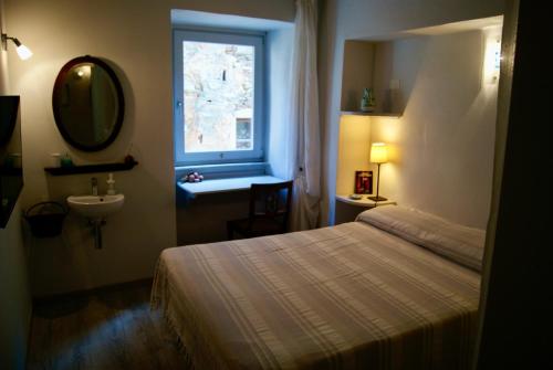 een slaapkamer met een bed, een wastafel en een raam bij L'appartamento sotto la Torre in Campiglia Marittima