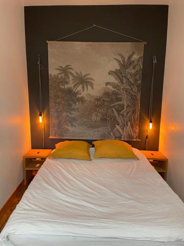 a bed with two yellow pillows and a painting on the wall at Maison de pêcheur proche du bourg in Ile aux Moines