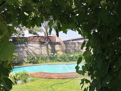 een zwembad in een tuin naast een muur bij The Private and Cosy Guest House 1 in Germiston