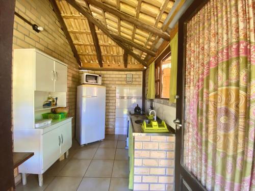a kitchen with a white refrigerator in a room at Haleakala Hostel & Pousada in Praia do Rosa