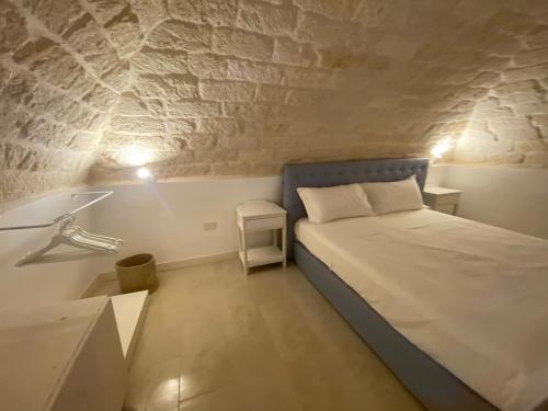 - une petite chambre avec un lit et un mur en pierre dans l'établissement A Casa del Console apartment, à Manfredonia
