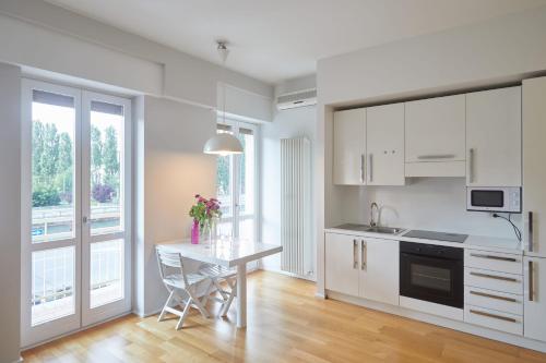 a kitchen with white cabinets and a table at appartamento incantevole sui navigli in Corsico