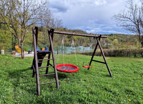 two swings in a yard with a table and a ladder at Pixie House - Mrežnica, private pier, hot tub in Gornji Zvečaj