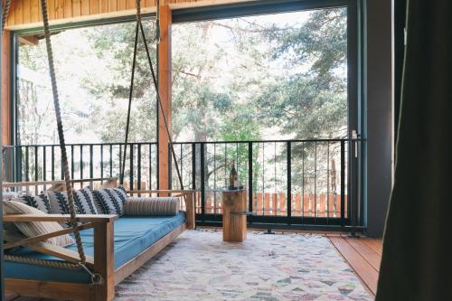 a porch with a swing in front of a large window at Dakota forest retreat in Tsigov Chark