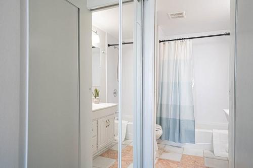 a white bathroom with a toilet and a shower at Waterfront Bliss, 2 BR Apt near Alki Beach in Seattle