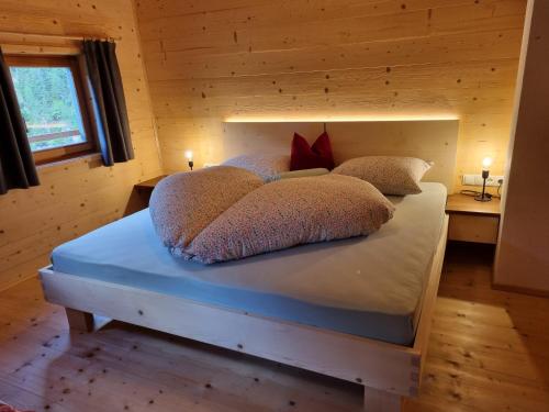 a bed with pillows on it in a wooden room at Bergchalet Englhof in Moso
