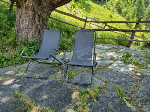 two chairs sitting on the ground next to a tree at Bergchalet Englhof in Moso